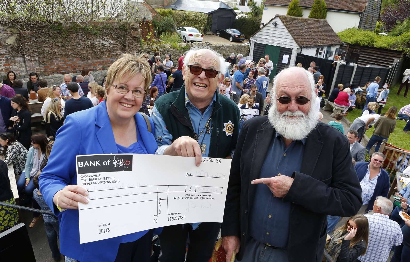 Ralph Steadman (centre) celebrates his 80th birthday at the Chequers in Loose, presenting Sue Shaw of the Heart Of Kent Hospice with a cheque for £3,000, with fellow artist Graham Clarke.