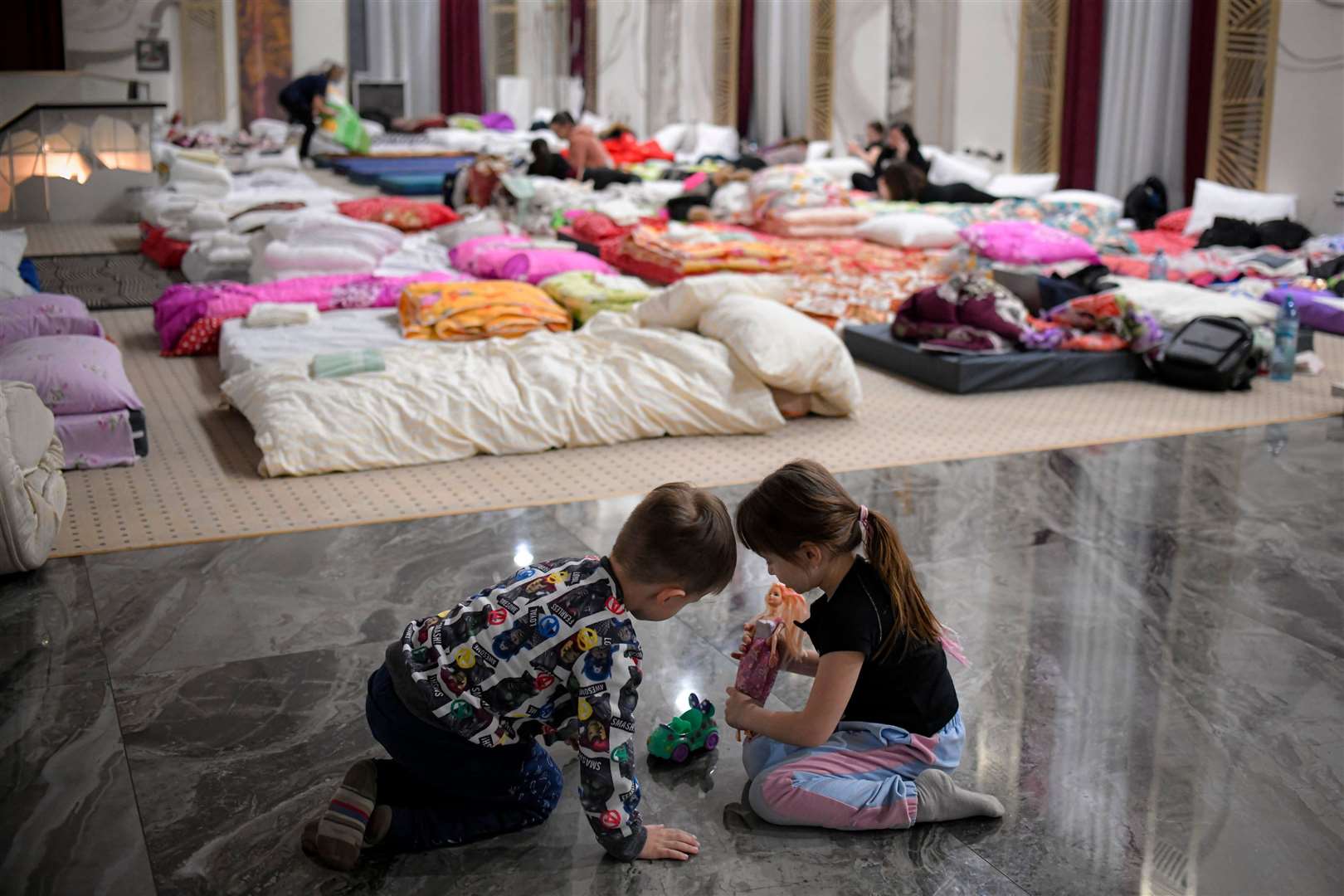 Children who fled the conflict from Ukraine play on the floor of an event hall in a hotel offering shelter in Siret, Romania. Picture: Andreea Alexandru/AP