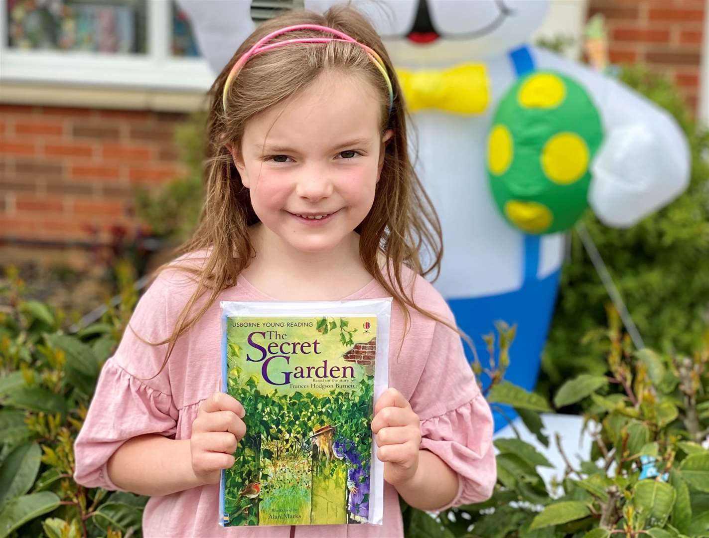 Six-year-old Emelia poses with the book The Secret Garden