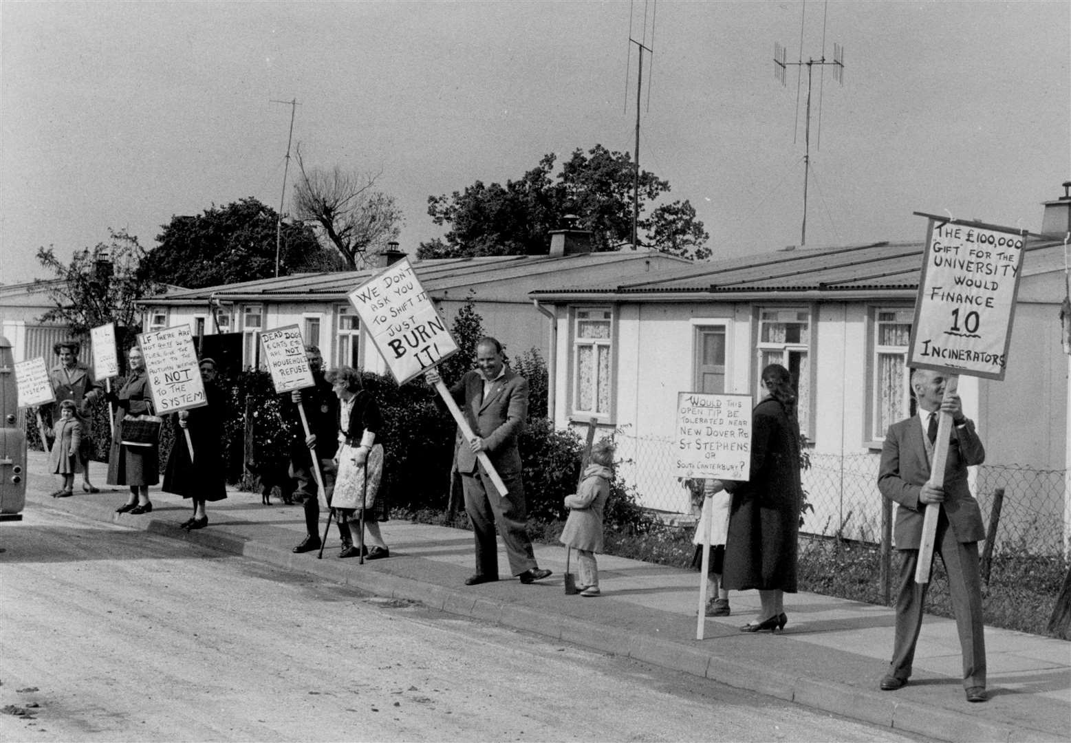 Residents protest about flies and smells at the rubbish dump at Tennyson Avenue, Canterbury, in September 1960. Their placards were aimed at councillors making an official inspection of the tip. Note the prefabs in the background