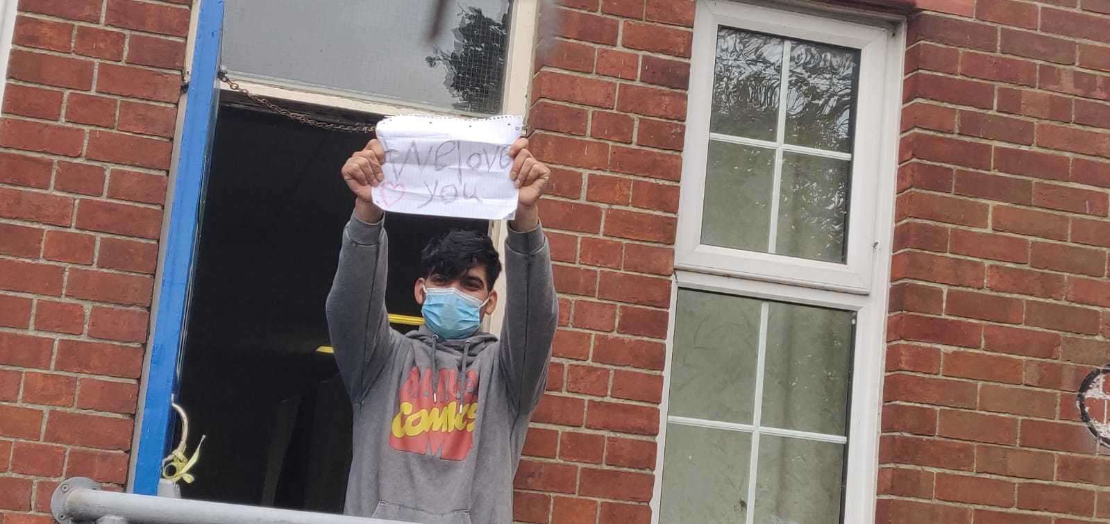 A refugee holds up a sign at Napier Barracks