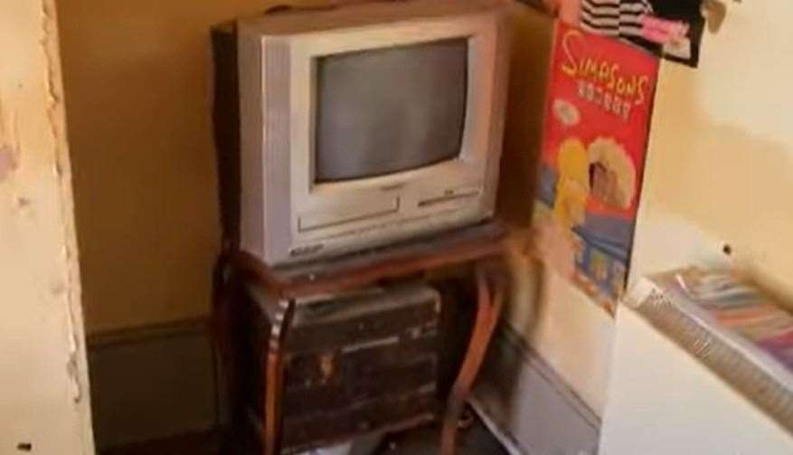 A built-in VHS TV and DVD players as well as a Simpsons poster.  Image: Clive Emson / YouTube