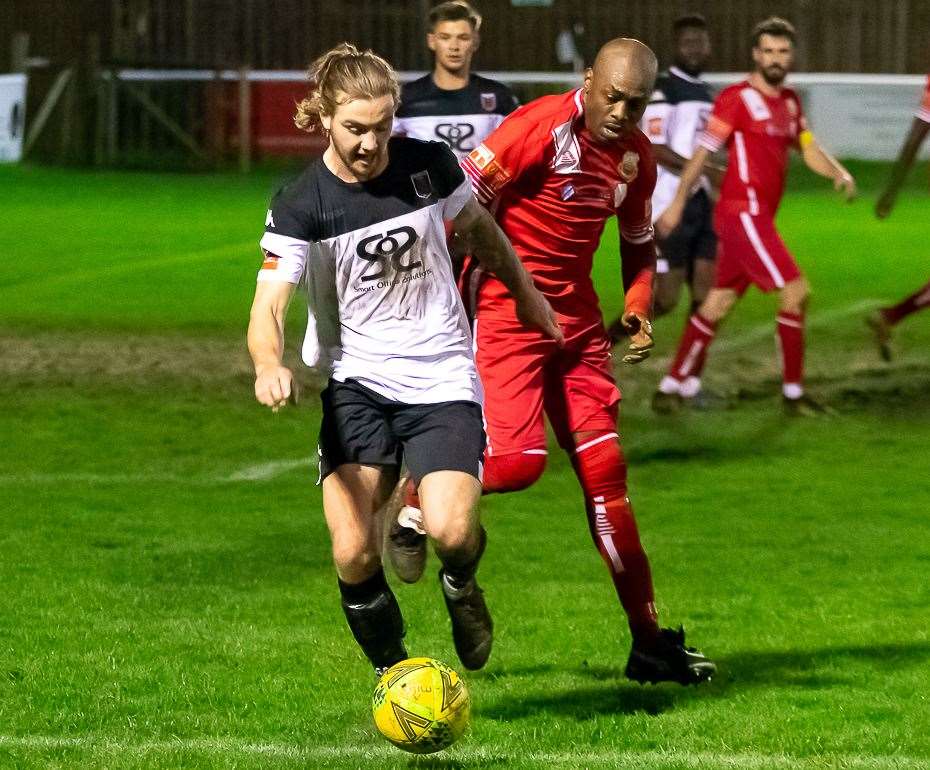 Faversham captain Lewis Chambers breaks out of defence under pressure from Whitstable's Junior Baker during the Lilywhites' 2-1 loss on Monday. Picture: Les Biggs