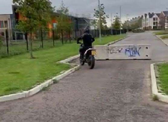 A biker on the wrong side of the barriers in Avocet Way, Ashford
