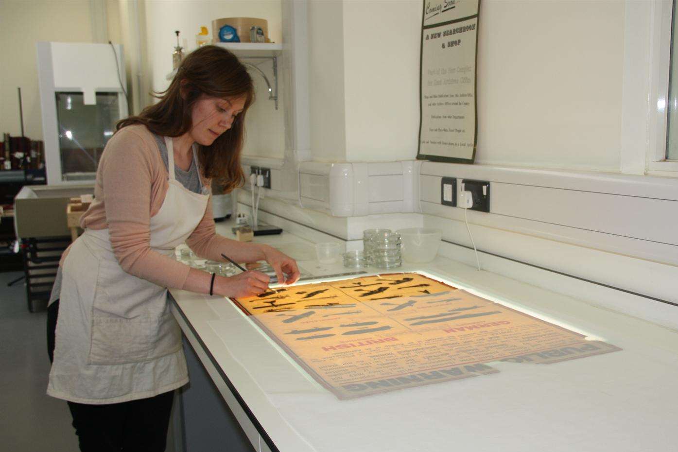 KCC conservation officer Macaulay Bristow works on restoring a poster from the First World War