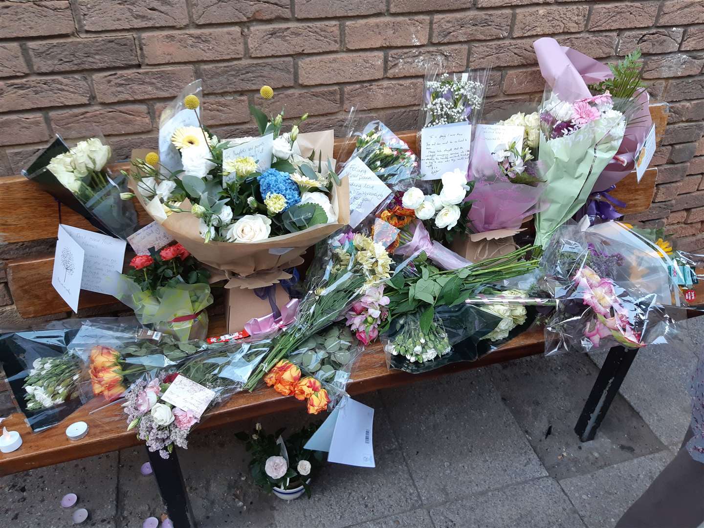Flower tributes cover a bench at the scene