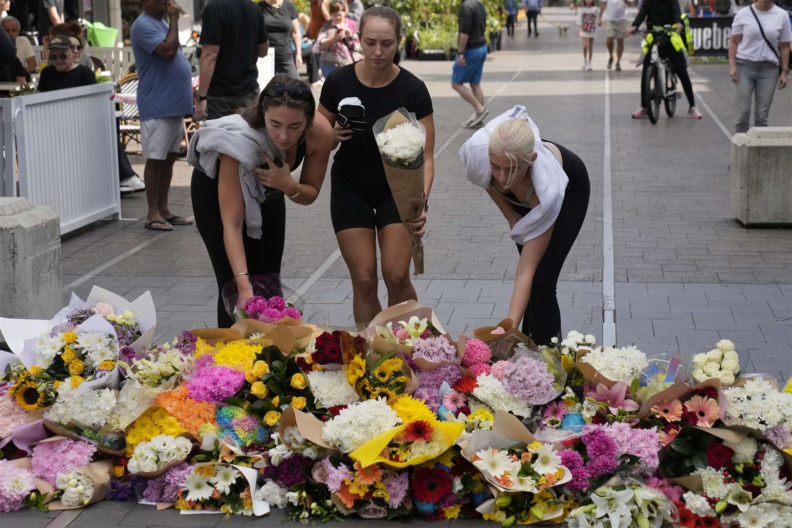 Three women place flowers at Bondi Junction in Sydney (Rick Rycroft/AP)