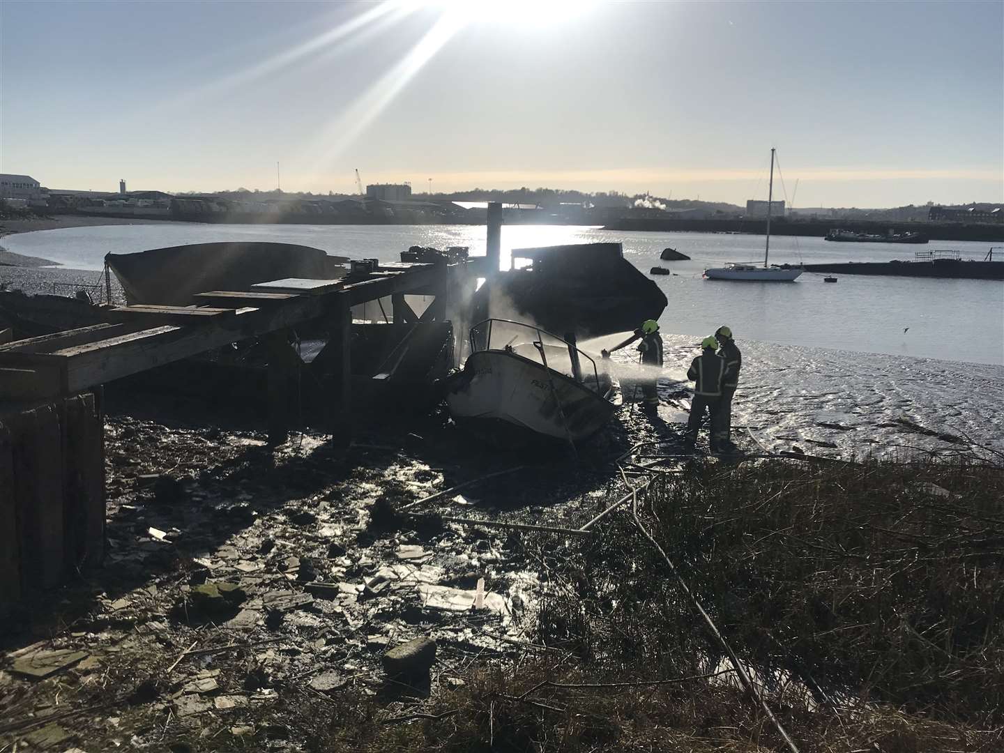 Firefighters hose down burnt-out boat