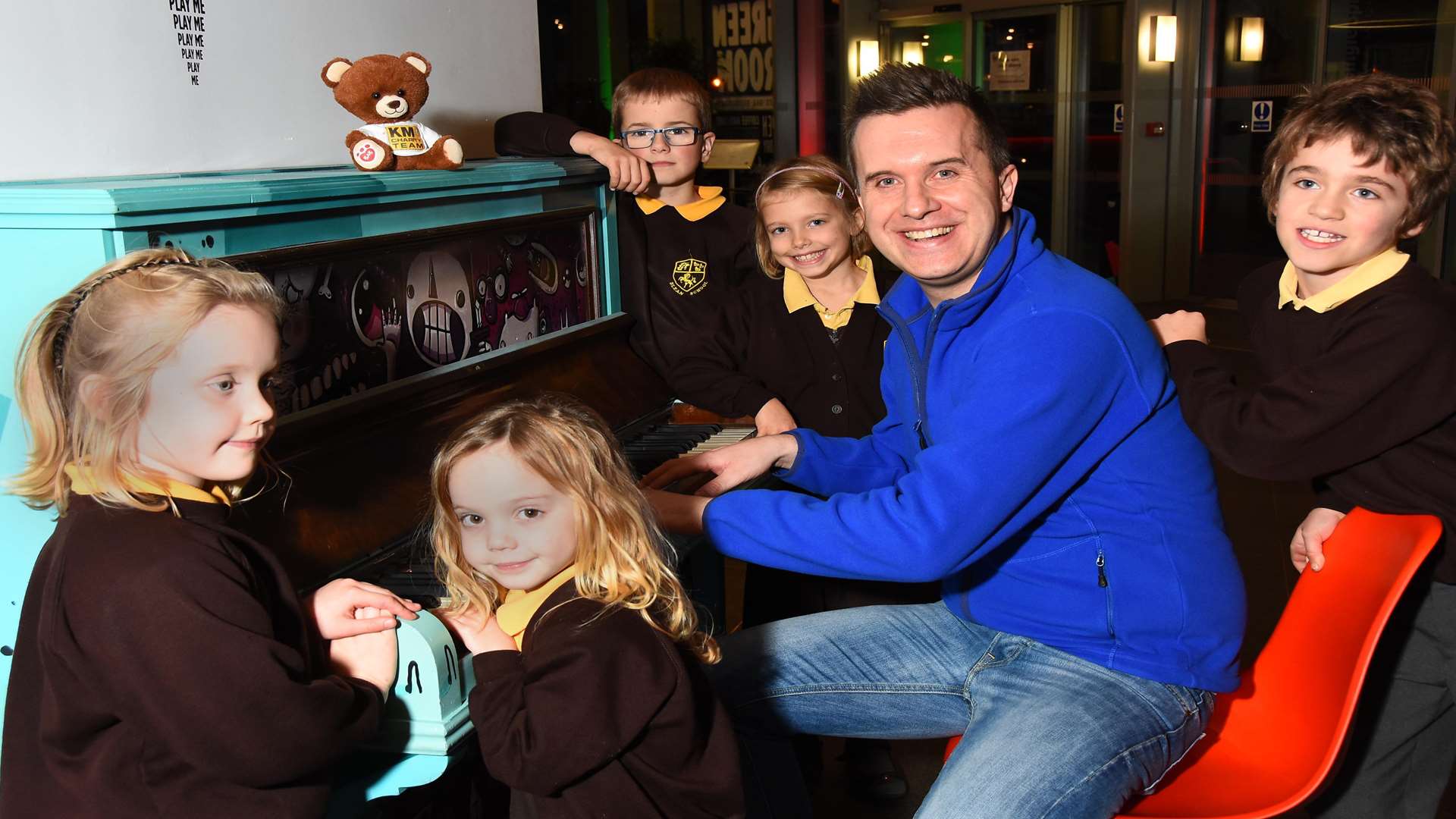 Phil Gallagher, star of Cbeebies' Mister Maker, performs a song on the piano with Blean Primary School. Children who partake in the KM Walk to School Song Contest can record their track professionally at a leading recording studio.
