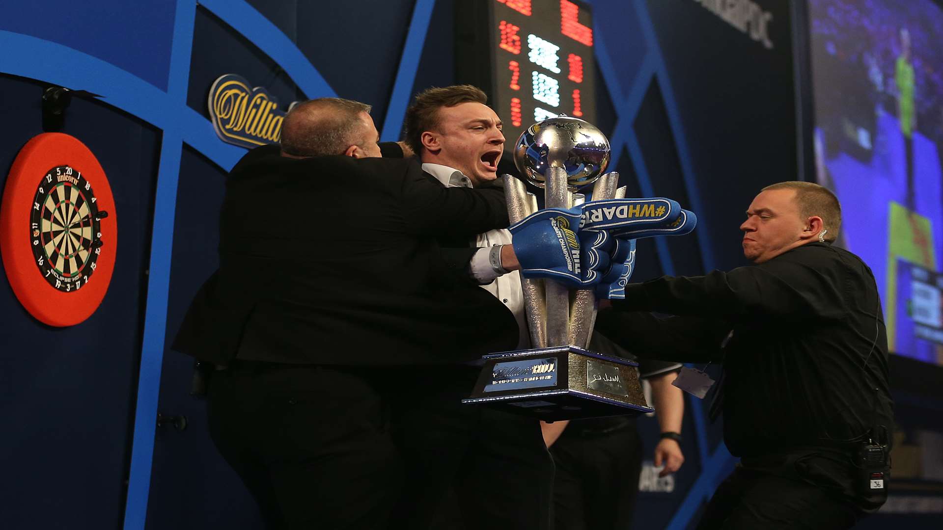 Lee Marshall is tackled by security after invading the stage at the world darts final. Credit: Steve Paston/PA Wire.
