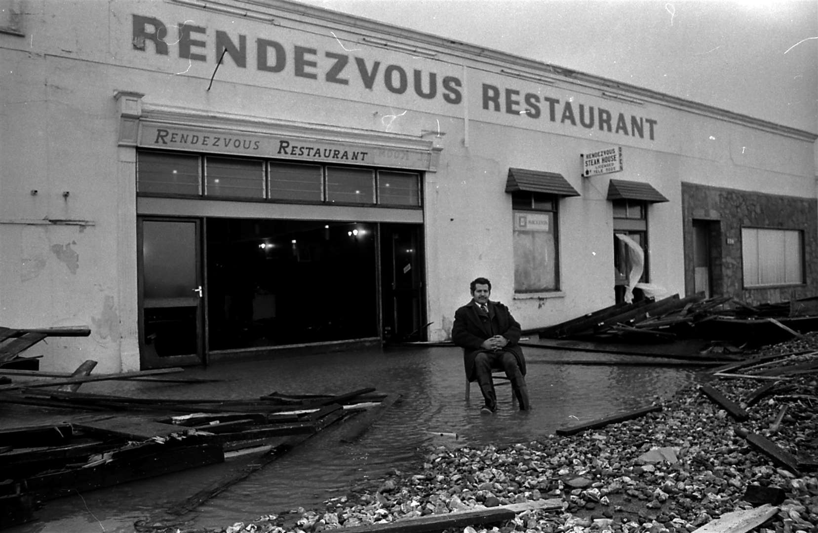 Peter Christofi sits outside his flooded Rendevous Restaurant at Herne Bay pier in January 1978