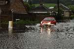 A car wades through the water after the bank holiday deluge