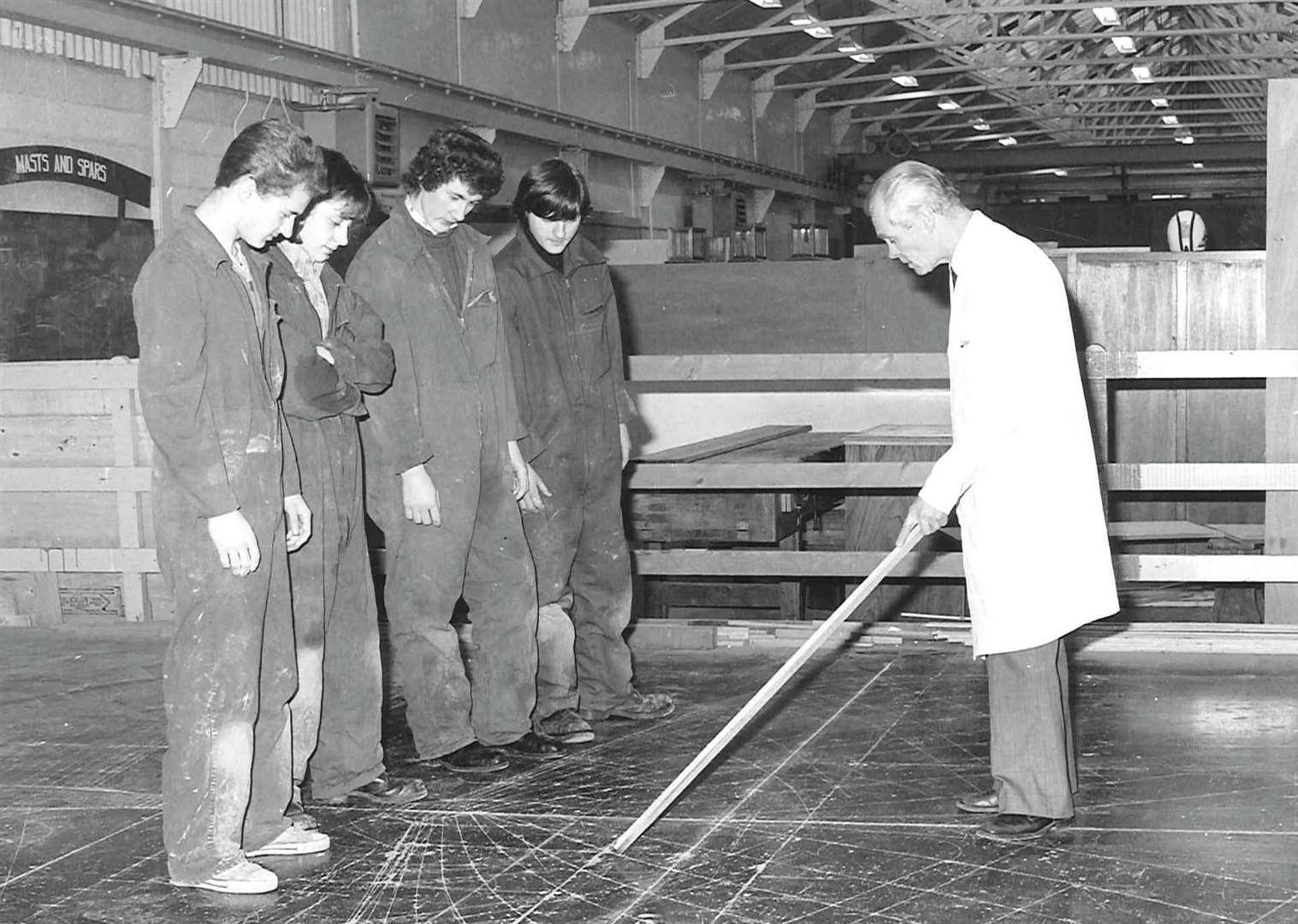 1970s shipwright apprentices with an instructor showing laying off on the mould loft floor. Dennis Jarvis is the instructor
