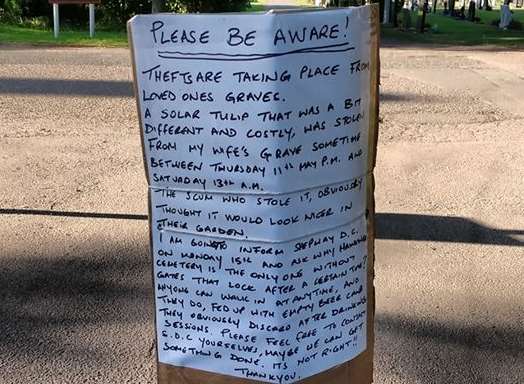 The handwritten sign was attached to a post at the cemetery over the weekend.