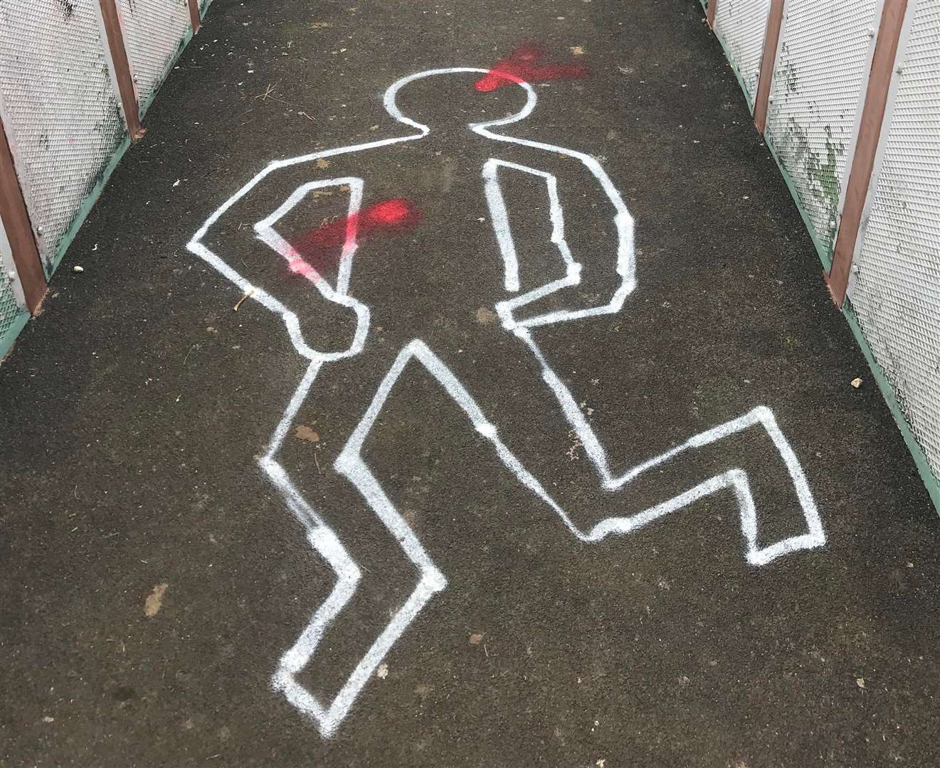 Graffiti resembling a 'dead body' outline of a crime scene has appeared across Faversham, including on the St Ann's footbridge. Picture: RJ Newman