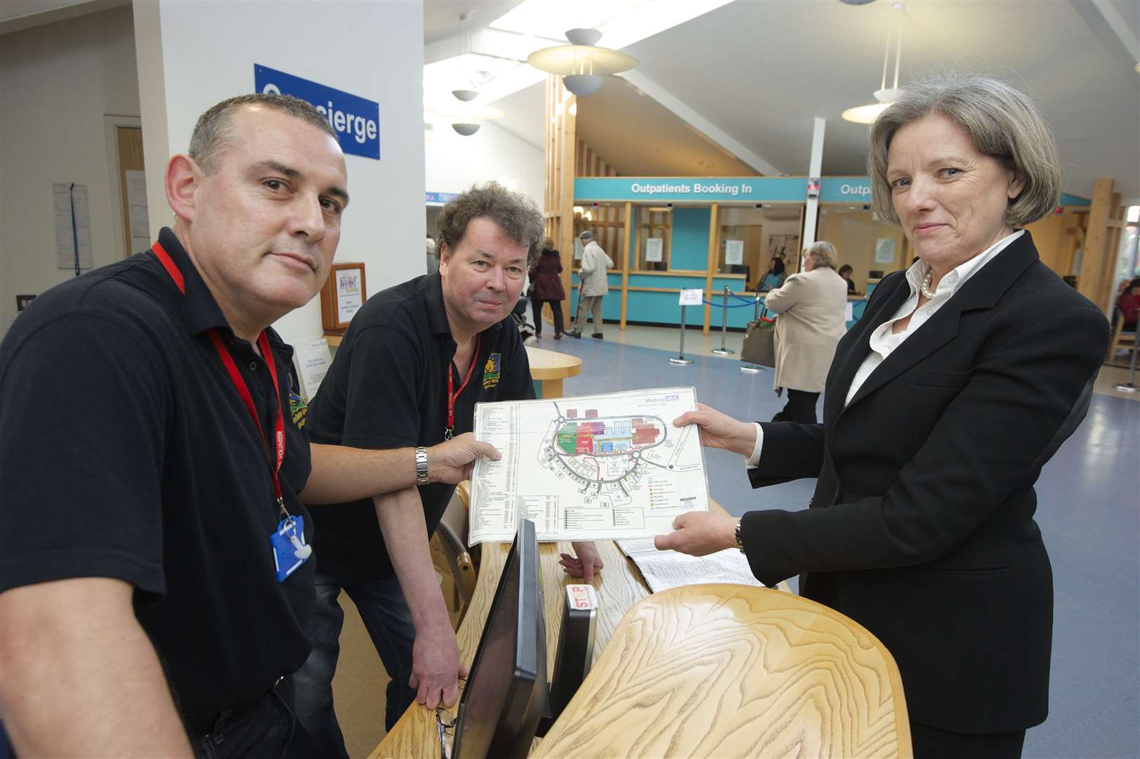 Volunteers Allan Filmer, left, and Willie Lambert with Shena Winning at the reception desk at Medway hospital