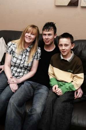 Smiling through: Sam with his mum and young brother Callum