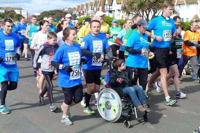 Christian Fortunato, six, is pushed round the Hastings Half-marathon course by Ashley Varley surrounded by supporters