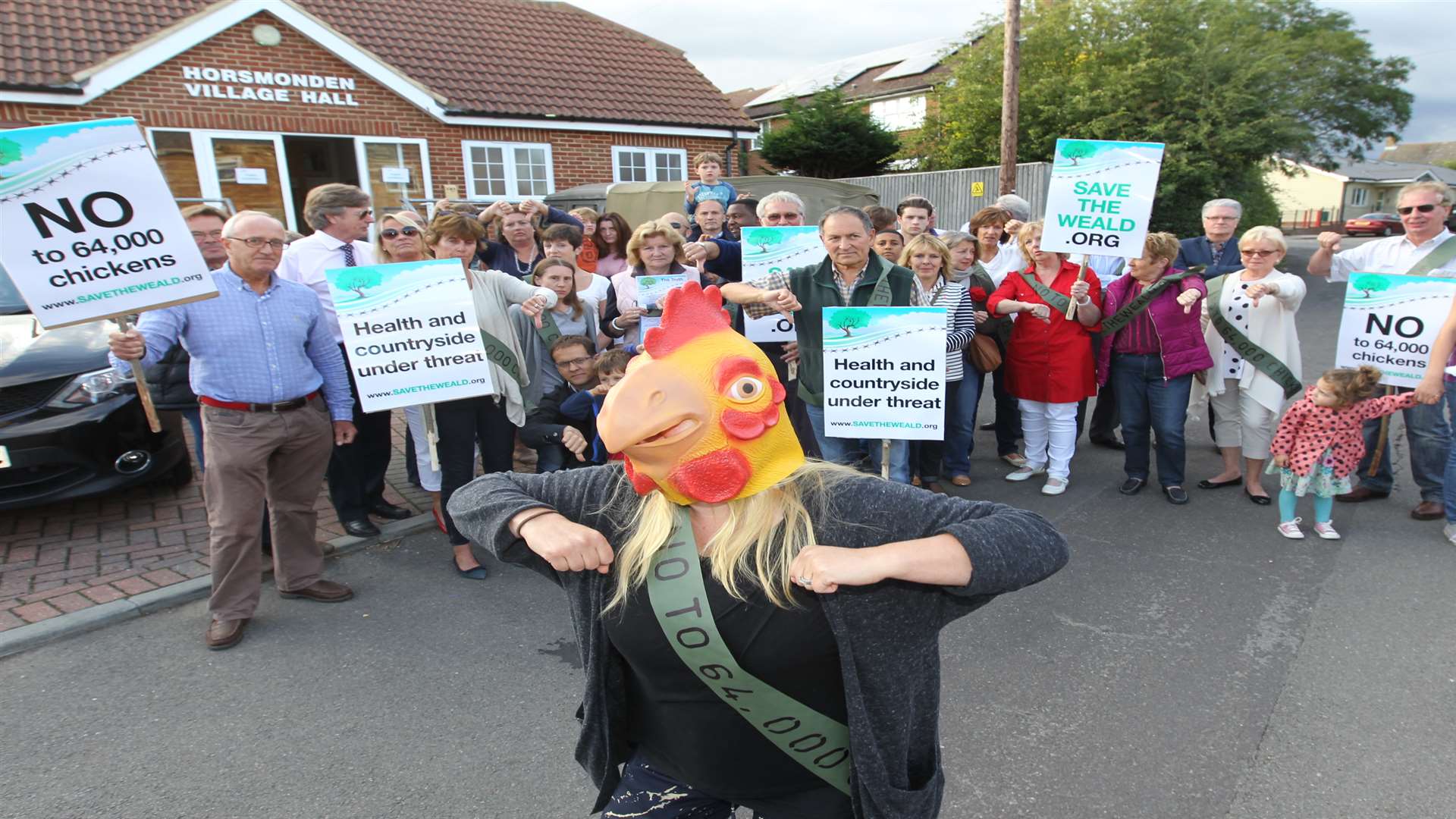 Penny Anderson, organiser, dressed partially as a chicken, with with other protesters outside a public exhibition for a large free range chicken farm proposal at Horsmonden Village Hall