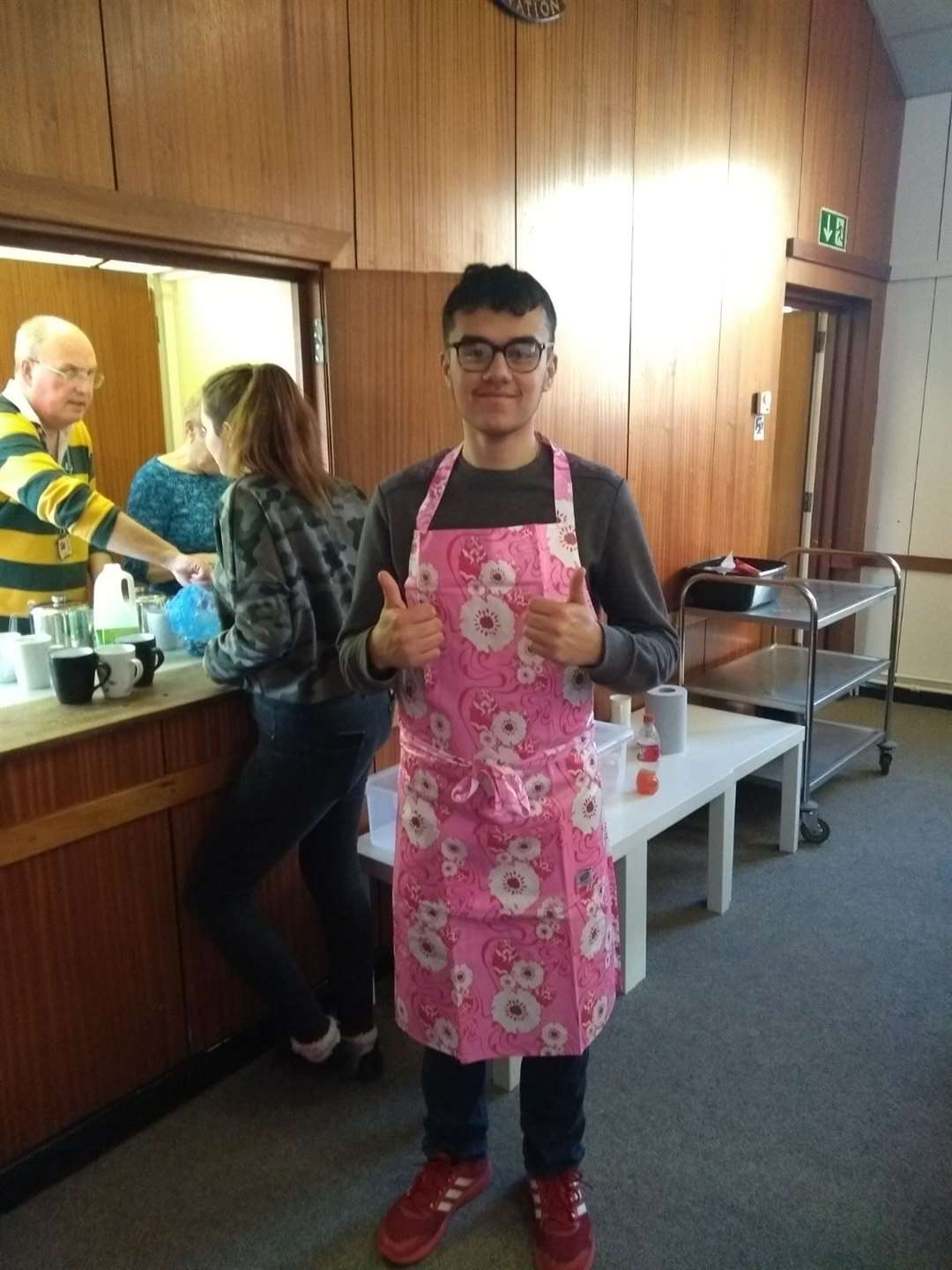 Emre Huseyin in pink apron serving at a community Sunday lunch at the Salvation Army Hall, Sheerness, with Paul Murray in the background