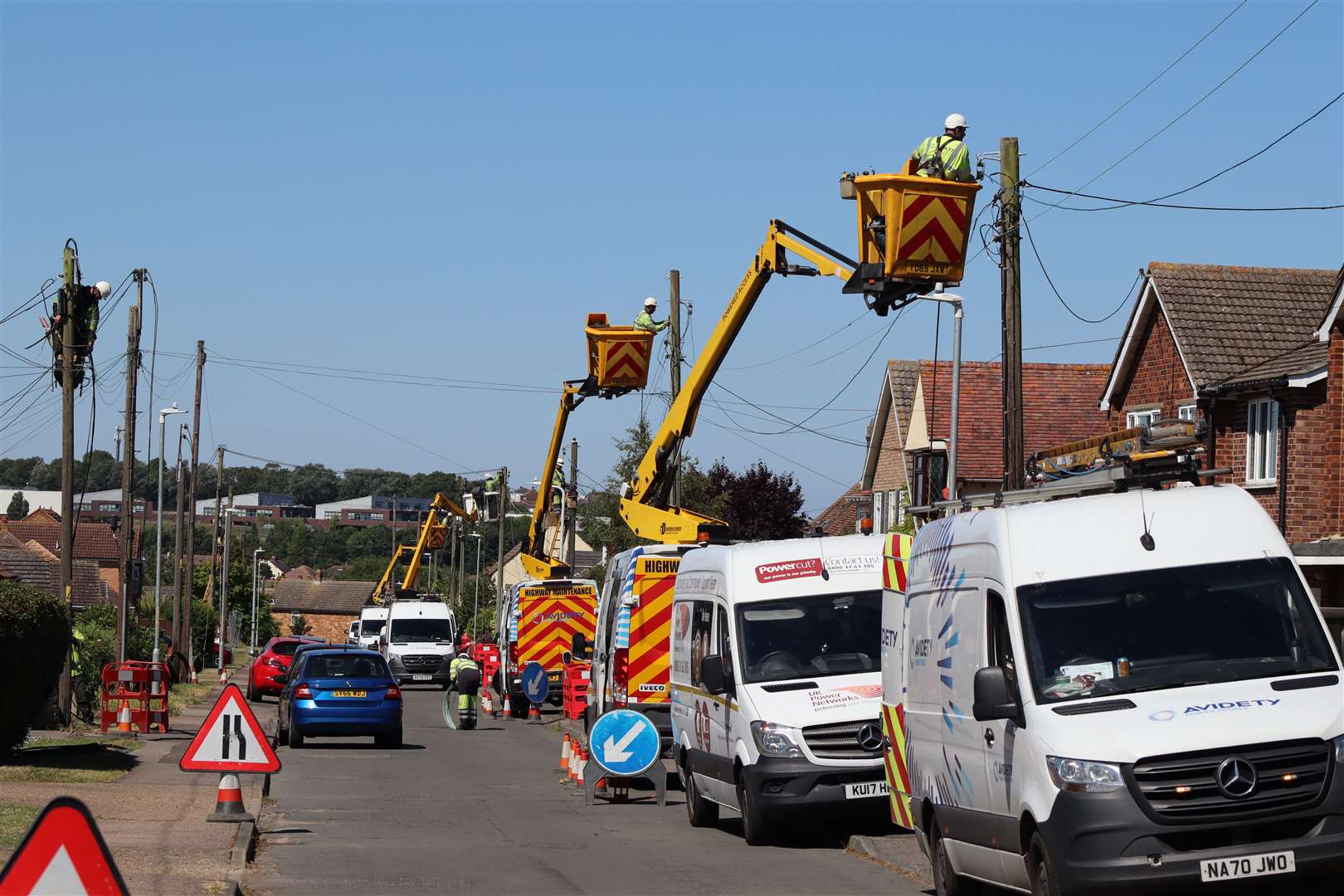 Engineers from Avidety using cherry pickers to string new electricity cables to poles for UK Power Networks