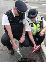 Two officers pouring alcopops down the drain