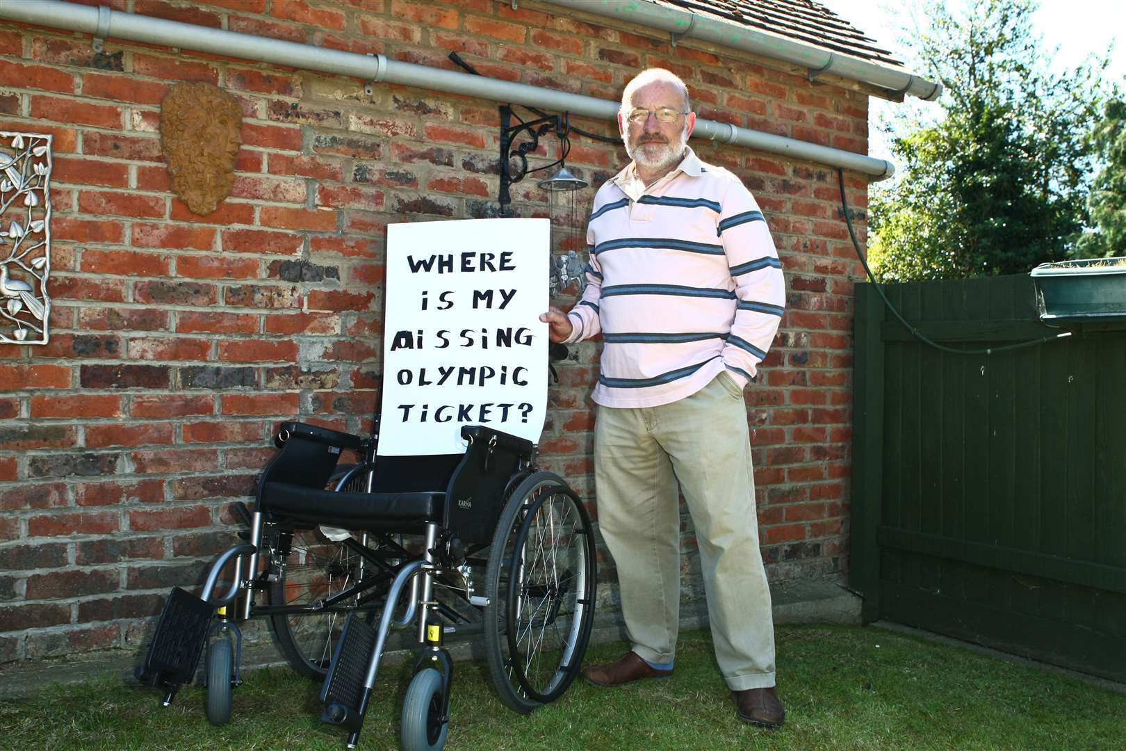 William Booth with a wheelchair and sign he held up during the Olympic torch relay. He had forked out £900 to see Michael Phelps at the Aquatics Centre but hadn't received a ticket