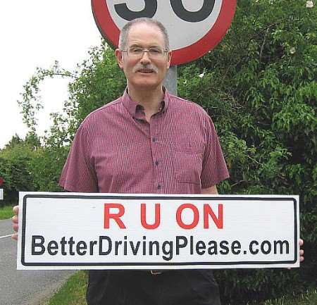 Andrew McGavin holding up a placard to get people to report dangerous drivers