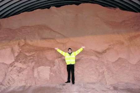 Reporter Keyan is dwarfed by the massive pile of salt