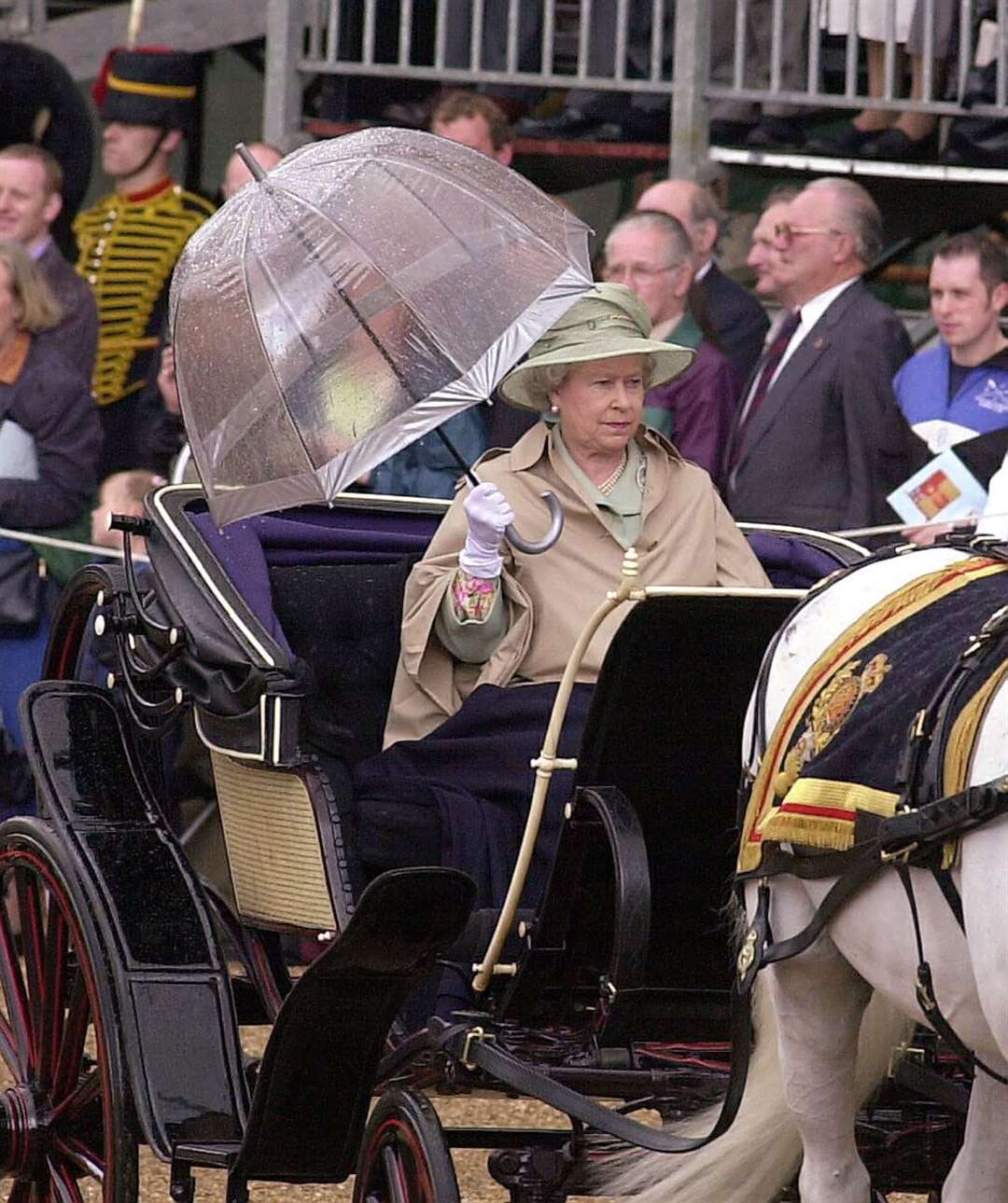 The Queen with an umbrella and a waterproof coat during a rainy carriage procession to Trooping in 2001 (Michael Stephens/PA)