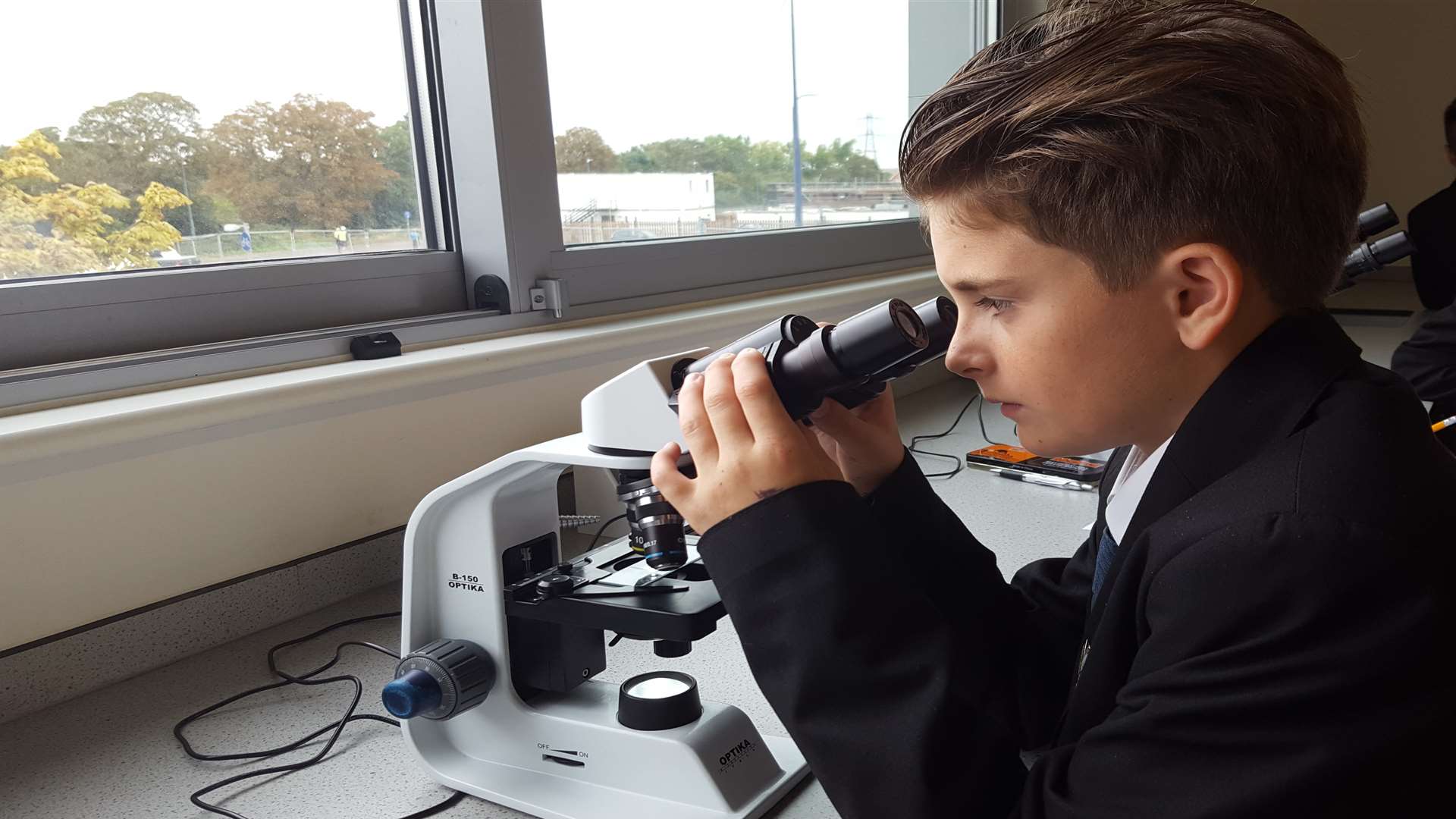 Thomas Barrett, 11, examines cells under the microscope in a science class