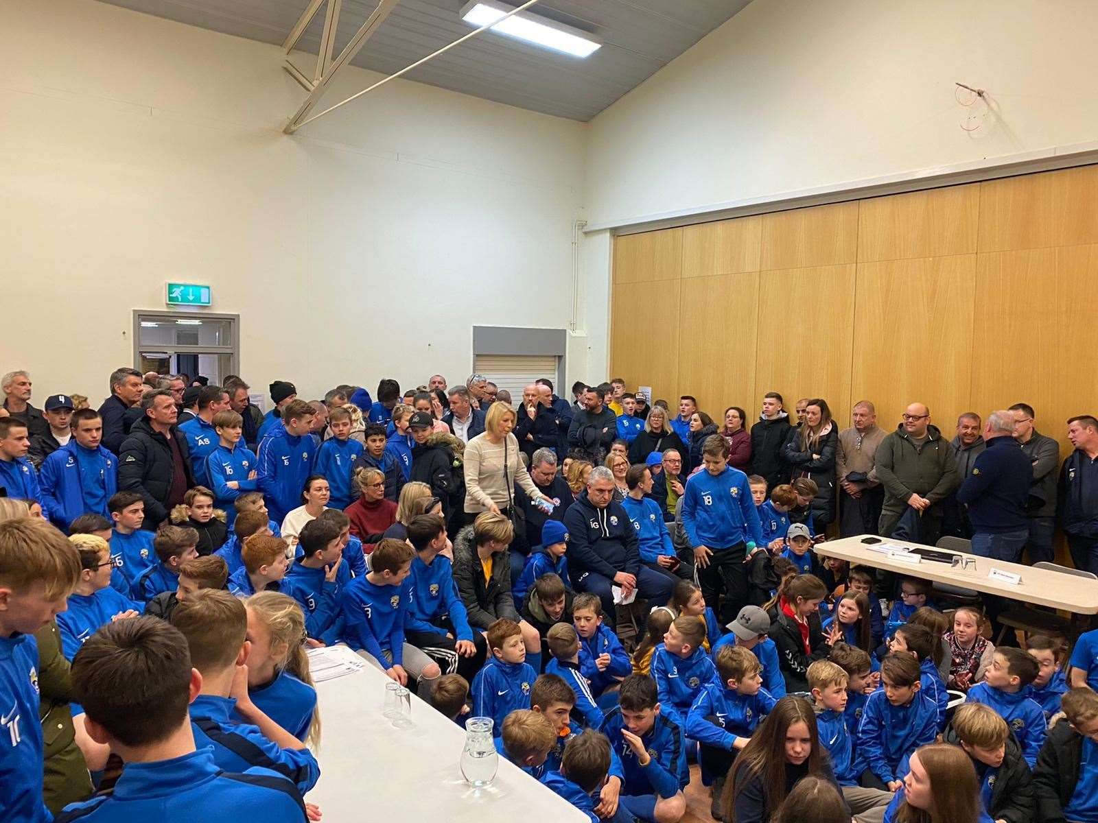 Dozens of young Kings Hill FC players pack into a village hall to stand up for their club