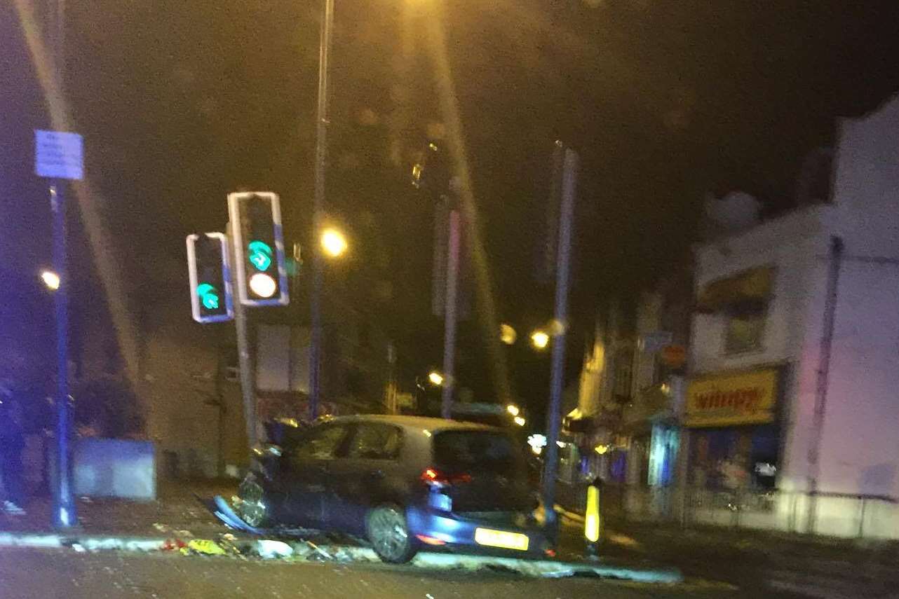 The black car hit a set of traffic lights