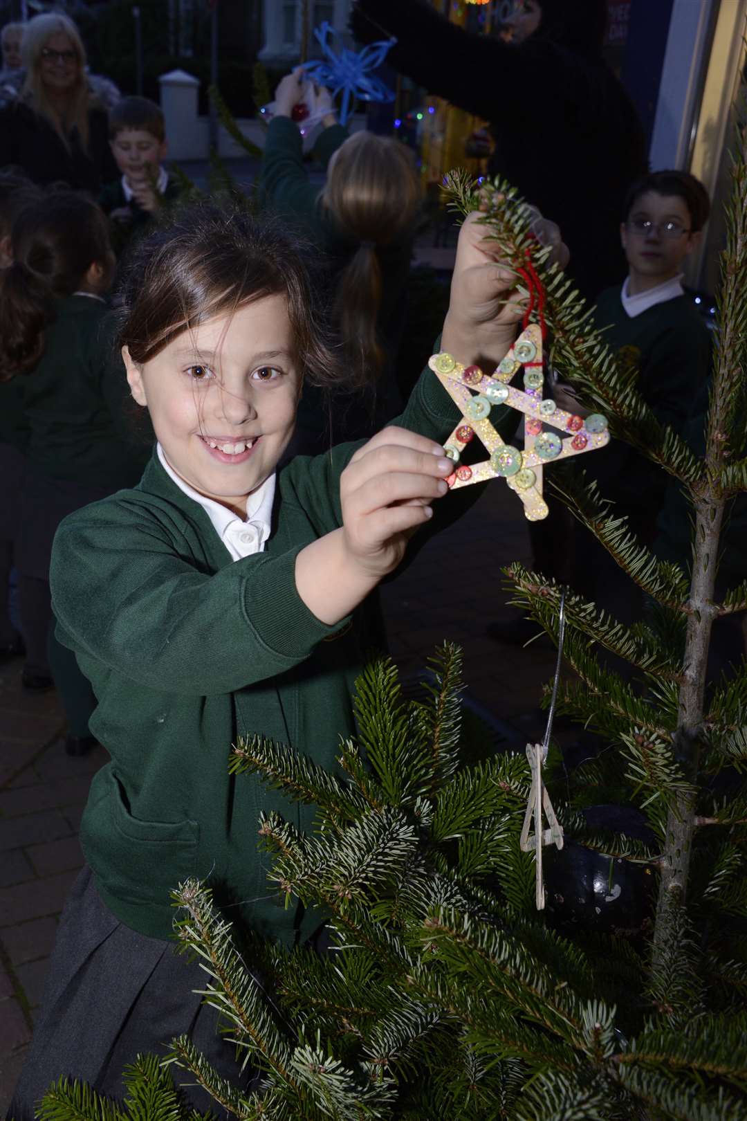 Adding sparkle to the High Street: Zoe Murray (nine) attaches a star to one of the Christmas trees that boutique owner Amanda Goring bought for passers by to admire