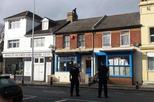 Black Bull Road in Folkestone has been closed after a man climbed on to a roof