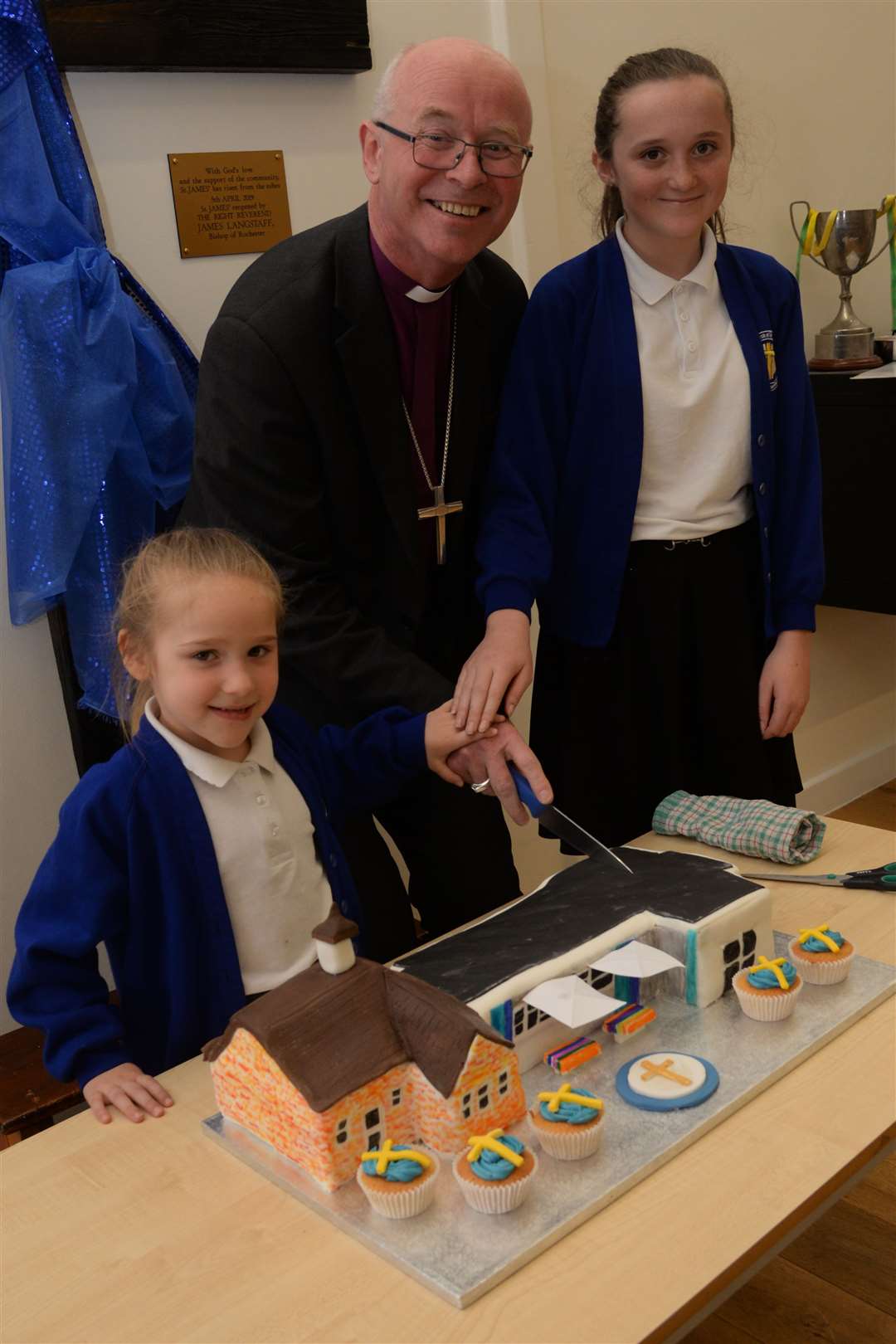 Two pupils help Bishop James of Rochester cut the cake Picture: Chris Davey