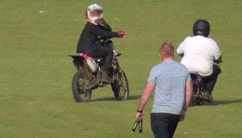 A motorcyclist gestures at a dog walker after riding past them at Barnfield Recreation Ground on September 3