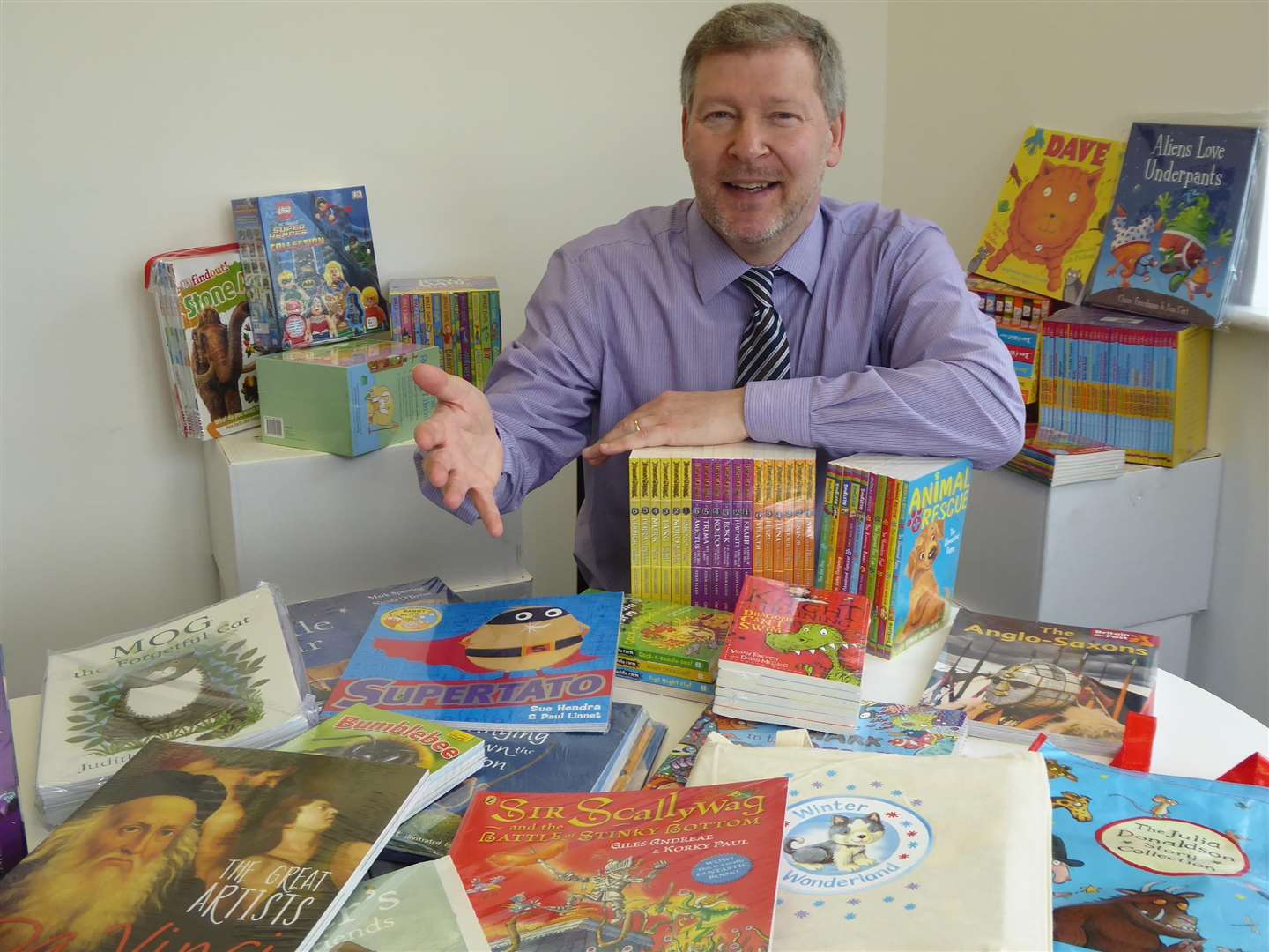 Simon Dolby, chief executive of the KM Charity Team, with the books to be won by a school joining Buster's Book Club.