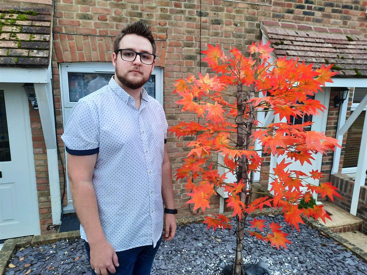 Tyler Erby stood next to the tree, which has been returned after it was stolen high vis-wearing thieves