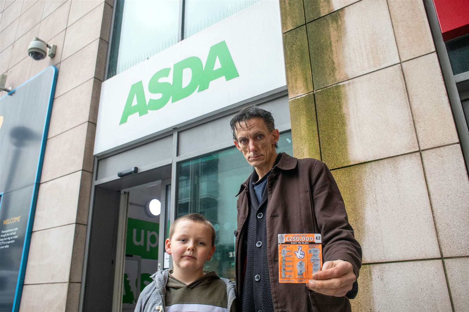 James Fletcher-Retallick and his seven-year-old son Ronnie, stood outside of the Asda in Folkestone that sold Ronnie a scratch card. Picture: SWNS