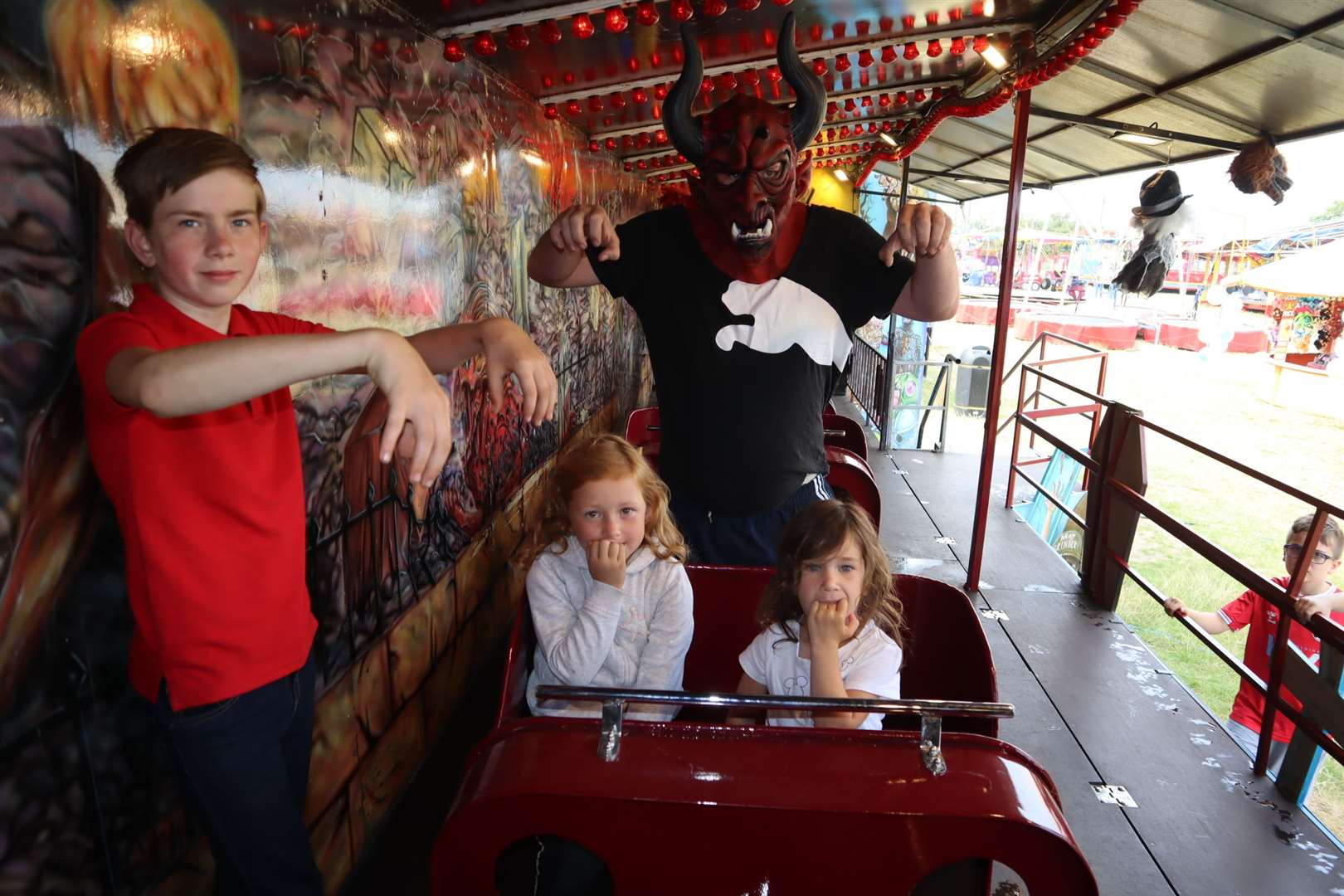 Devil Steve Gibbs, 38, from Hoo practises his "Hell-o" on the Graveyard Express ghost train at Leysdown, Sheppey, watched by the train's station master Reece Brett, 12, and guinea pigs Darcey Christian, 6, and her cousin Crystal Christian, 4