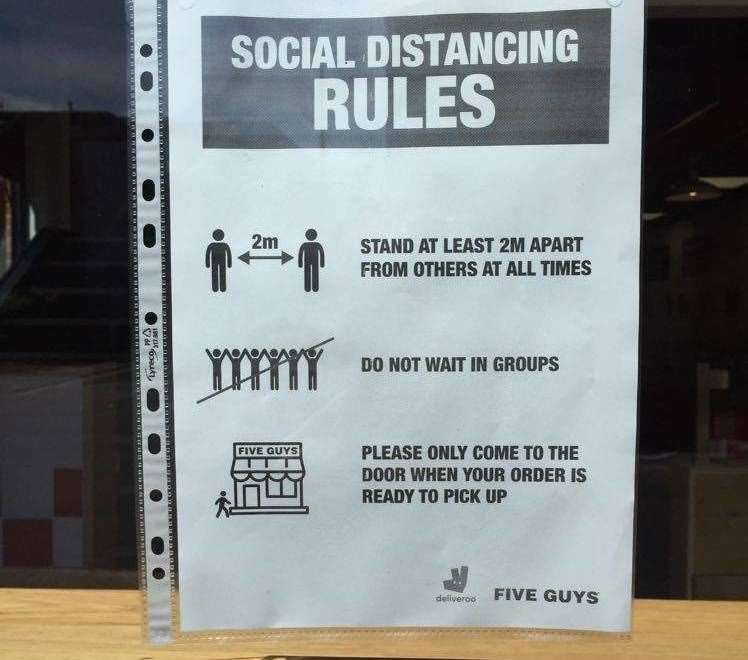 Posters reminding customers of social distancing rules are displayed in the windows
