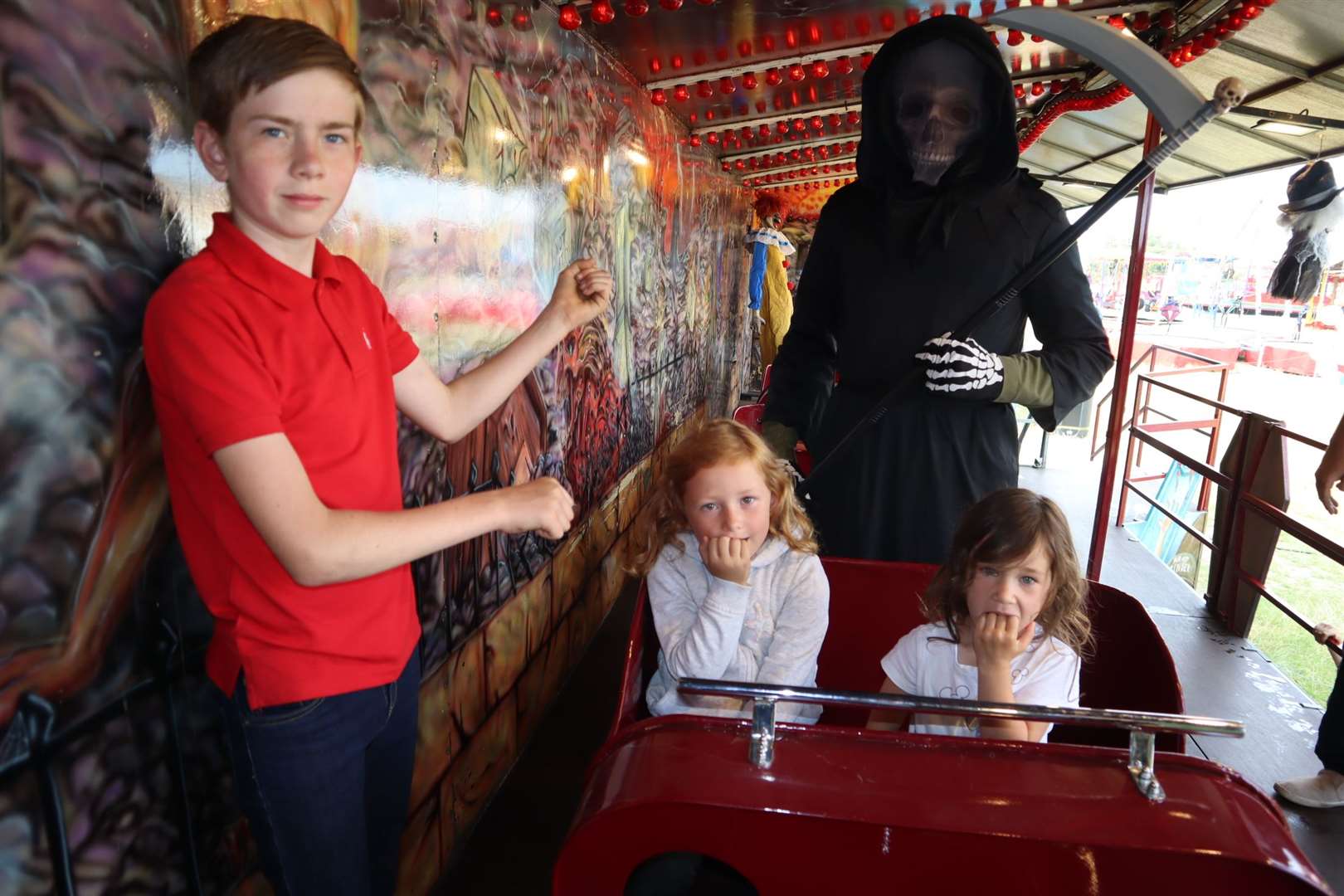 Death stare from the Grim Reaper Oscar Bennett, 17, from Warden Bay at the Graveyard Express ghost train at Leysdown, Sheppey, watched by the train's station master Reece Brett, 12, and guinea pigs Darcey Christian, 6, and her cousin Crystal Christian, 4