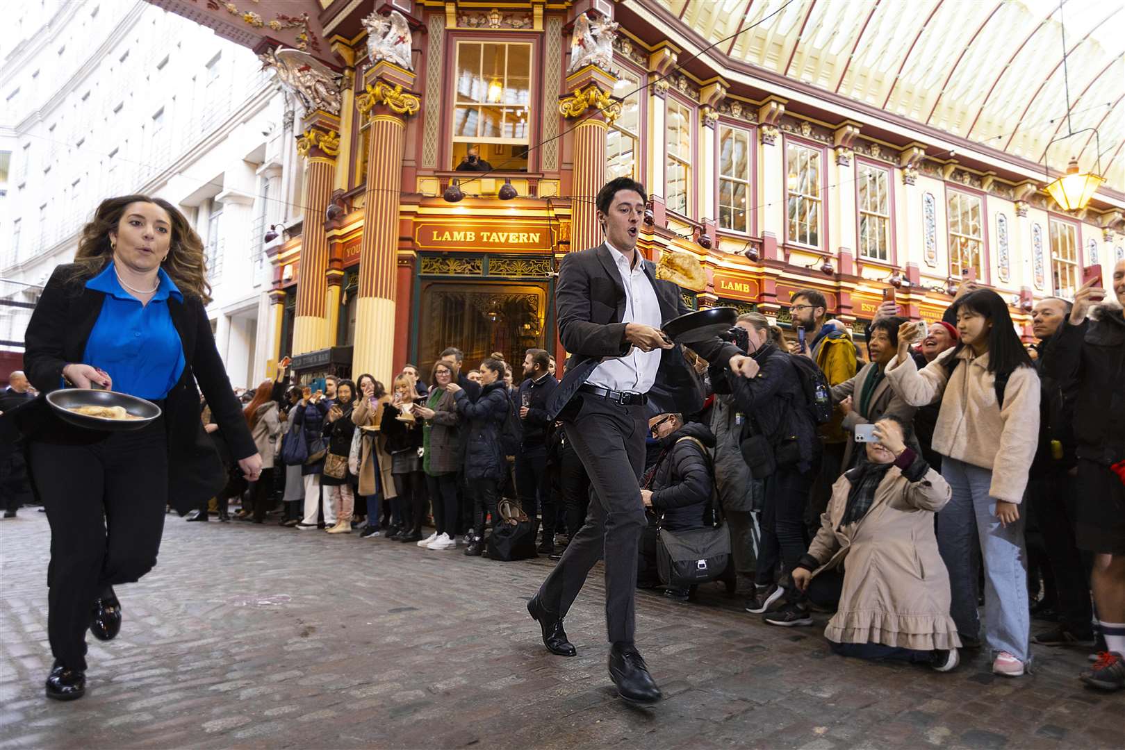 Two well-dressed individuals vying for the golden frying pan trophy at the yearly Leadenhall Market pancake race in London in February (PA)