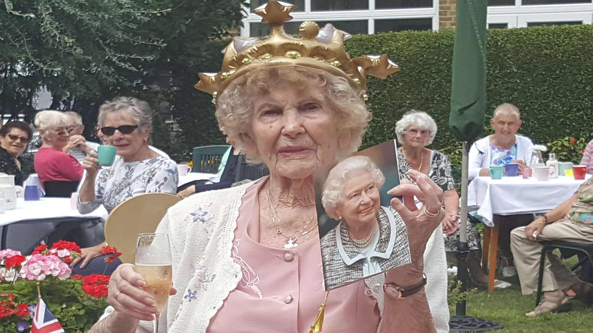 Marjorie Beton celebrates her 100th birthday with a glass of champagne, a crown and a card from the Queen
