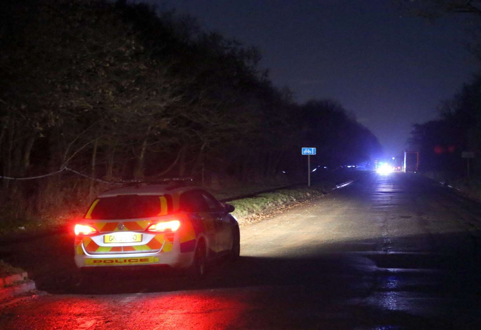 The picture shows the police tape stretching all the way along the wooded area and path (Picture: UKNIP)