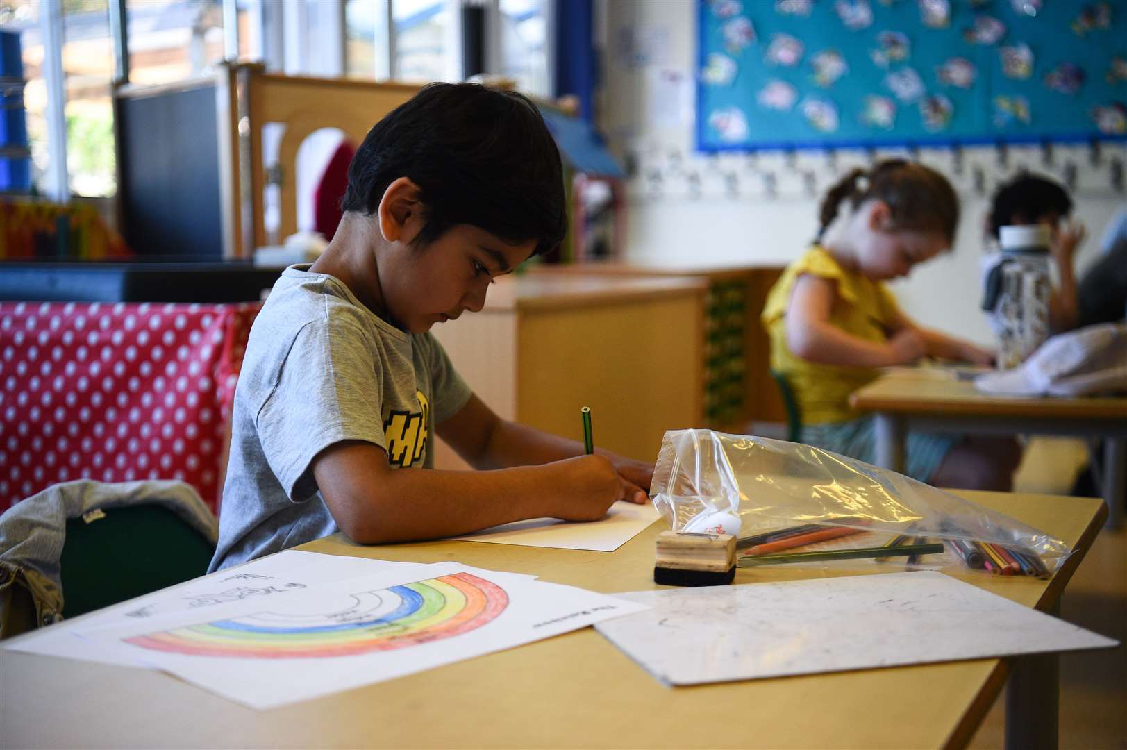 Pupils draw rainbows as they sit at separate desks at Hiltingbury Infant School in Hampshire (Kirsty O’Connor/PA)