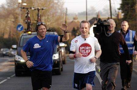 John Bishop waves to fans as he runs through Higham with comedian Frank Skinner on Thursday afternoon.