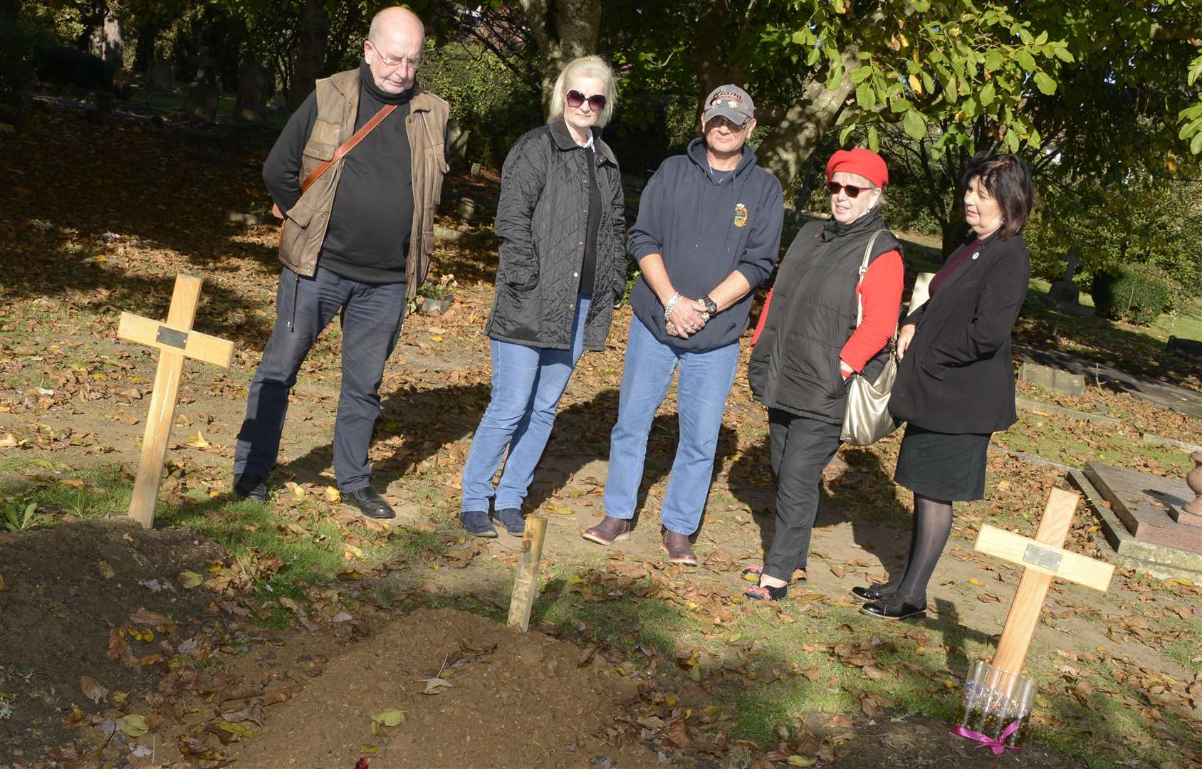 Delia Parker-Bailey, second left, with friends and neighbours by the unmarked grave