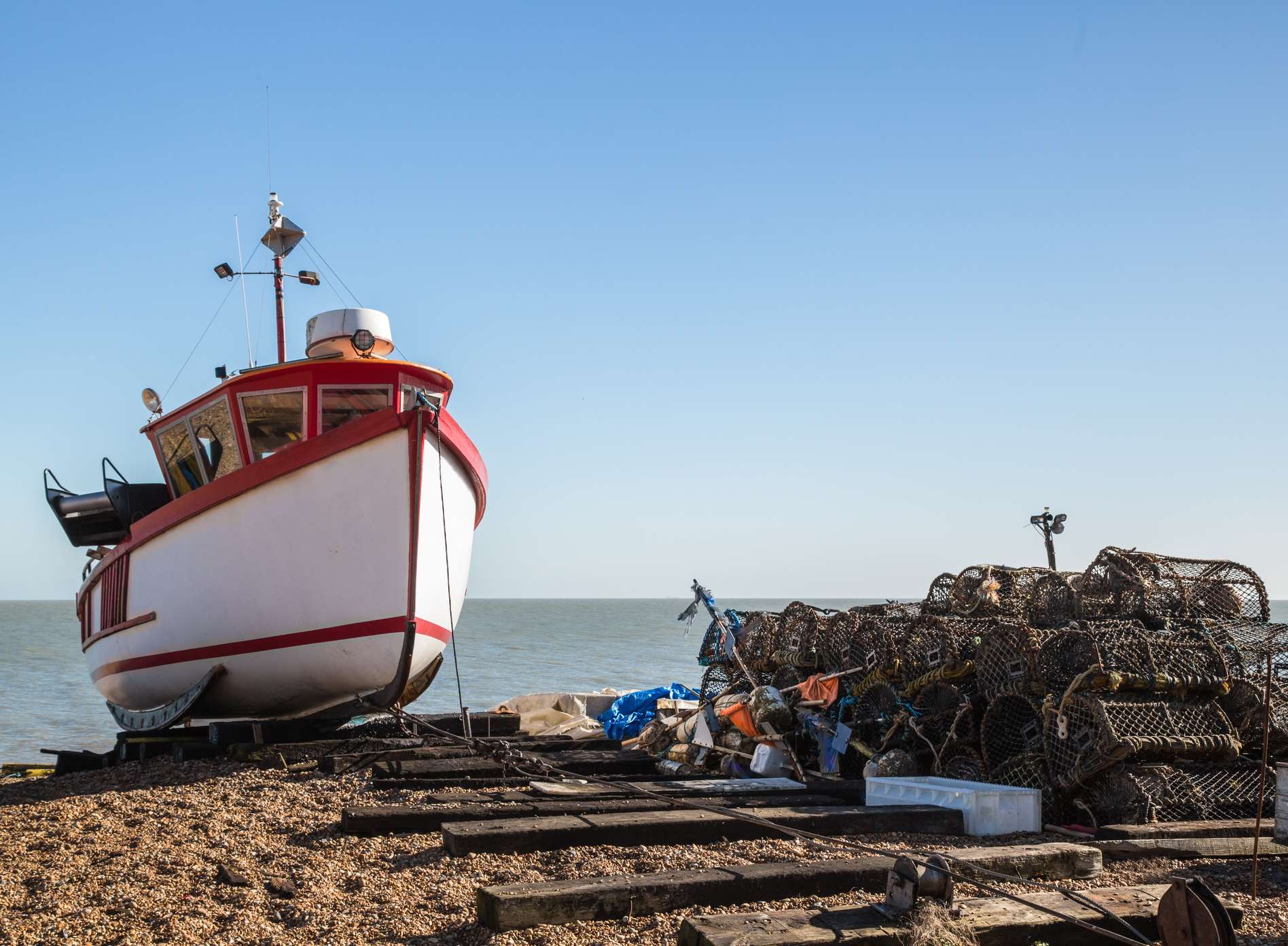 A fishing boat and lobster nets on the beach at Deal